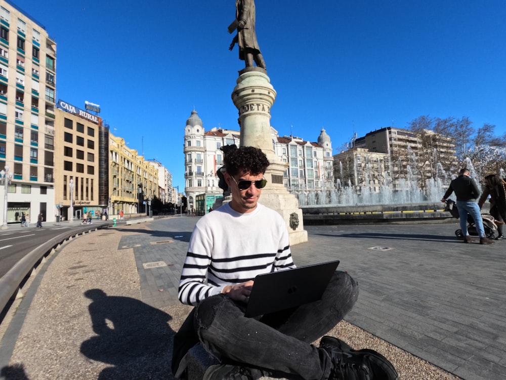 a man sitting on the ground using a laptop