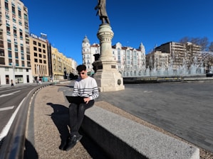 a man sitting on a ledge using a laptop computer