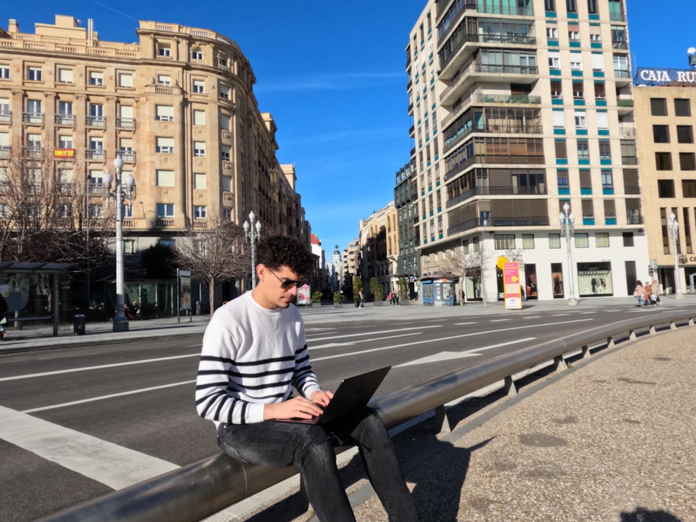 a man sitting on a bench using a laptop computer