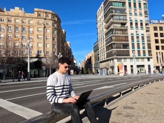 a man sitting on a bench using a laptop computer