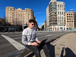 a man sitting on a rail in the middle of a city