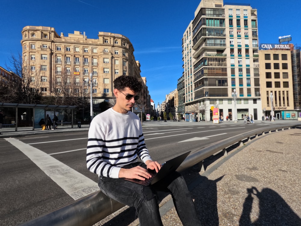 un hombre sentado en una barandilla en medio de una ciudad