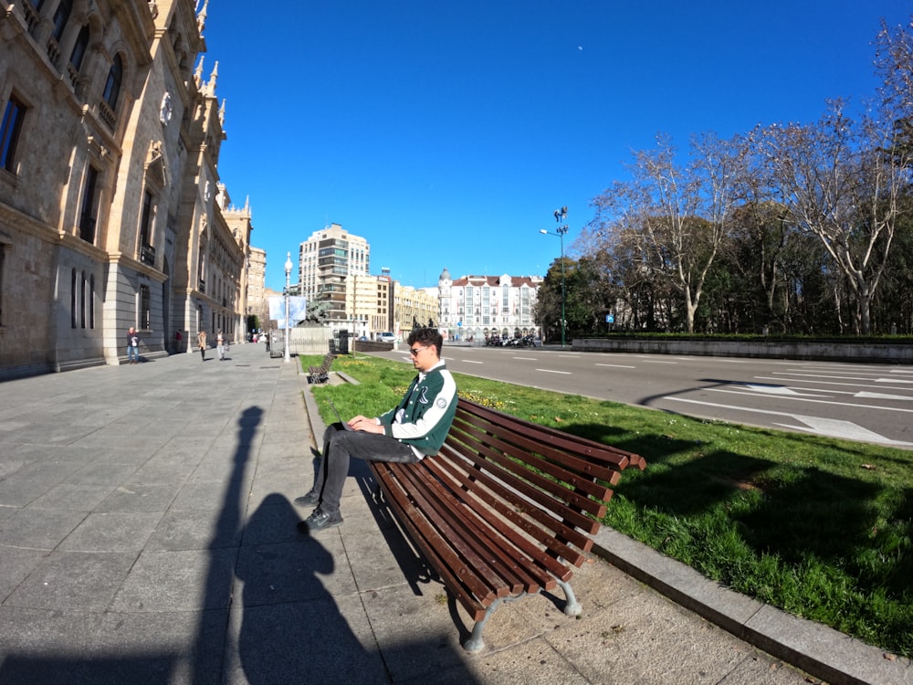 a man sitting on top of a wooden bench