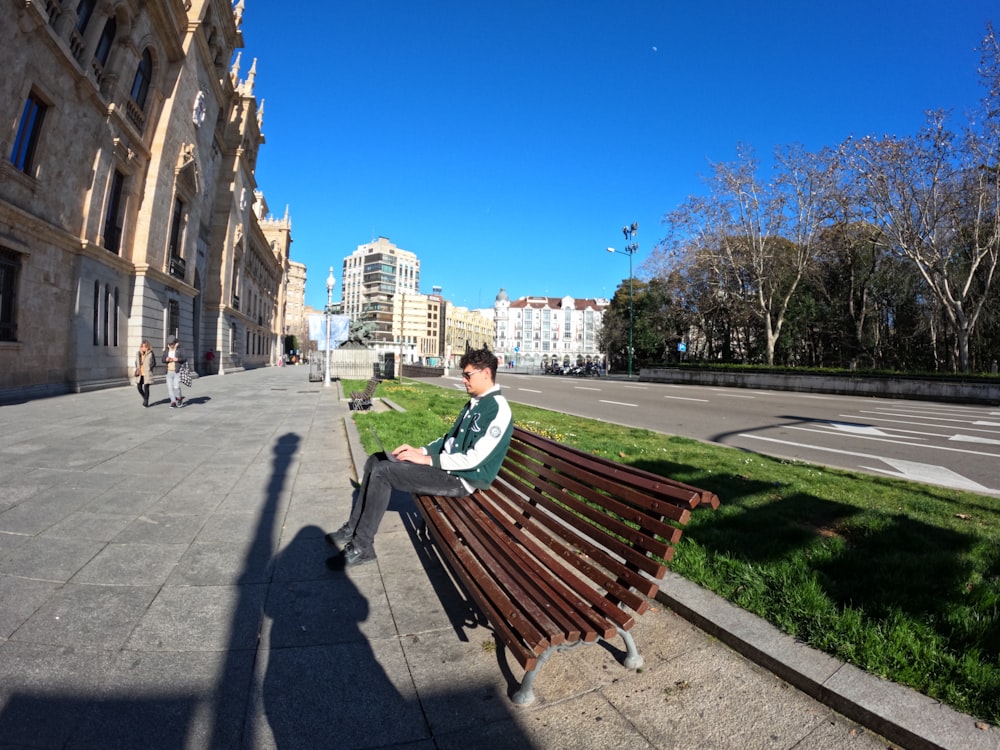a man sitting on top of a wooden bench