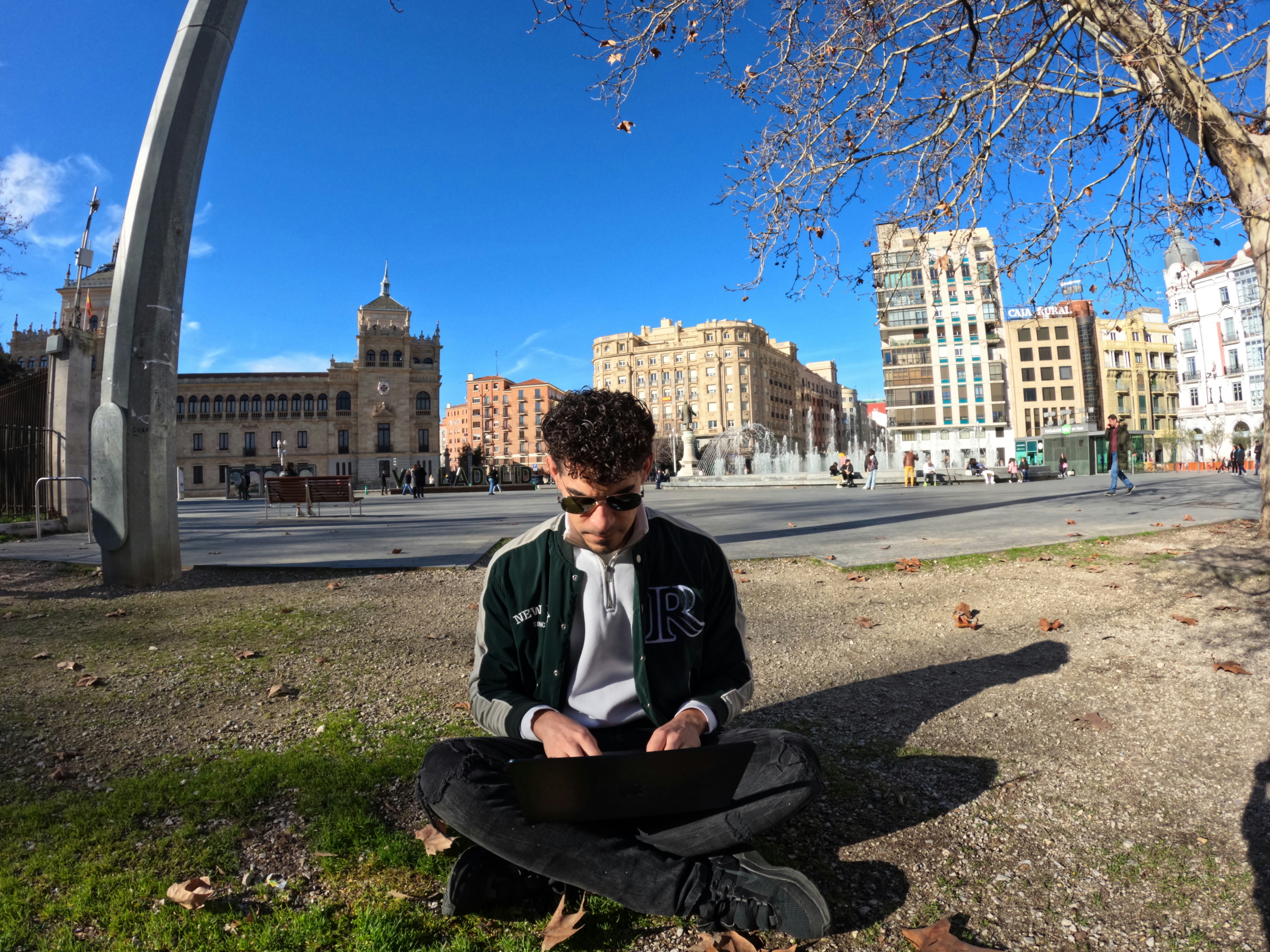 a man sitting on the ground looking at his laptop