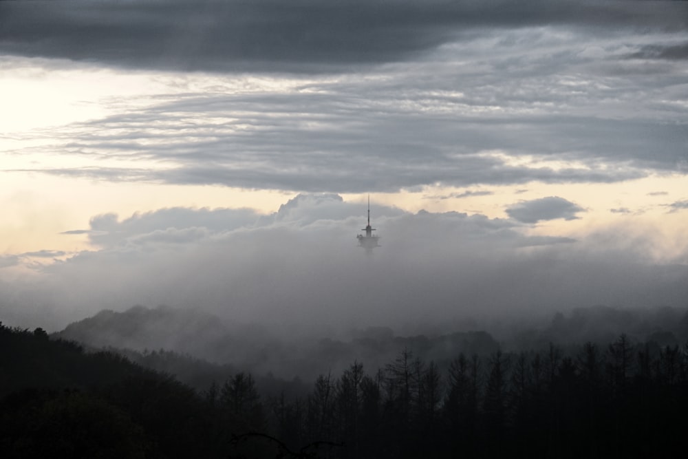 a view of a foggy mountain with a tower in the distance