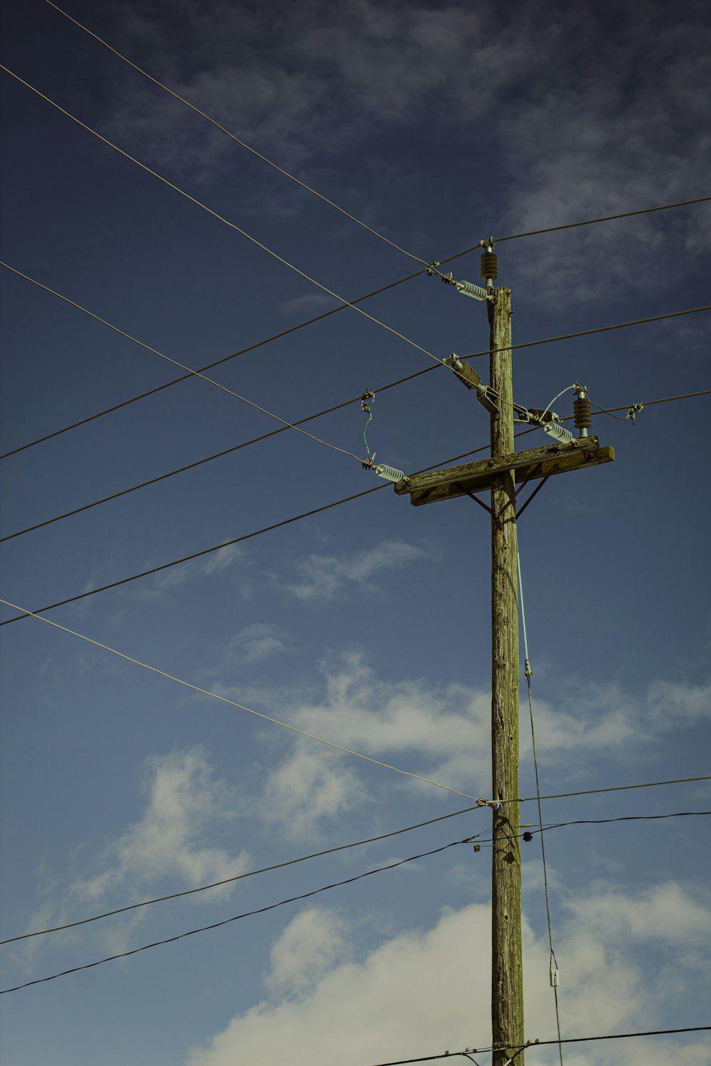 a wooden cross on a pole with power lines in the background