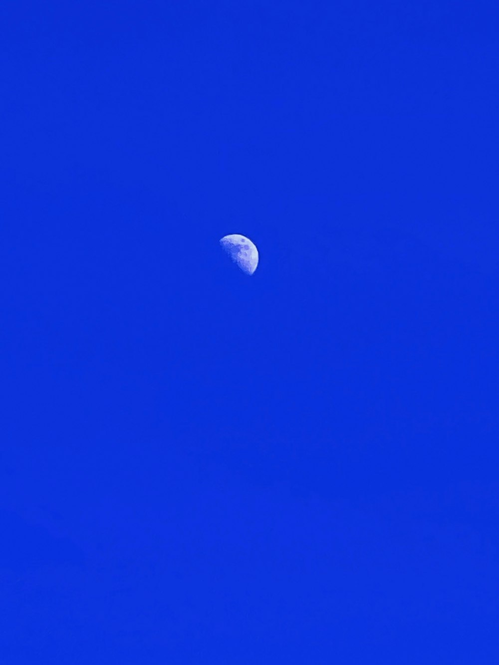 a blue sky with a half moon in the middle