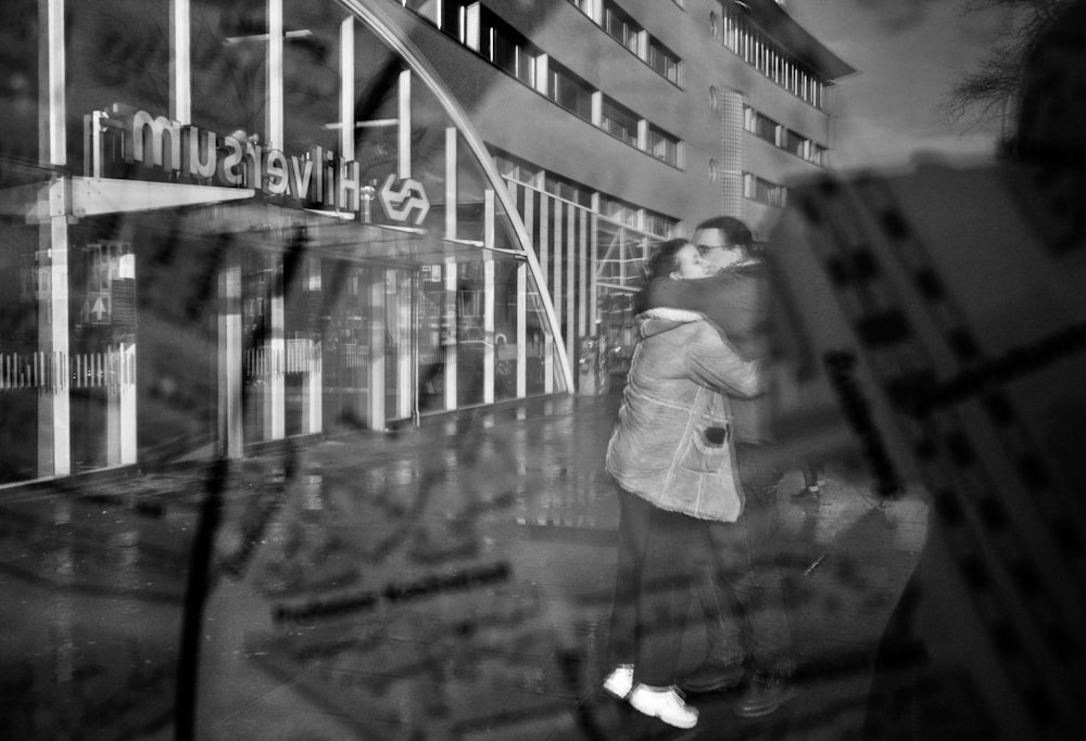 a black and white photo of a woman standing in front of a building