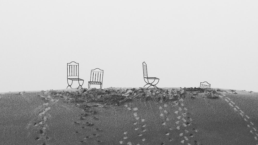 three chairs sitting on top of a sandy beach