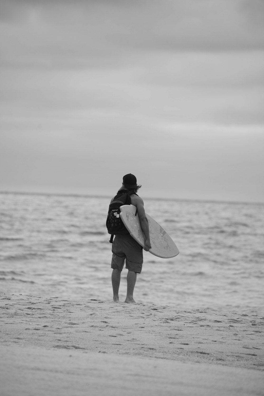 모래사장 위에서 서핑보드를 들고 있는 남자