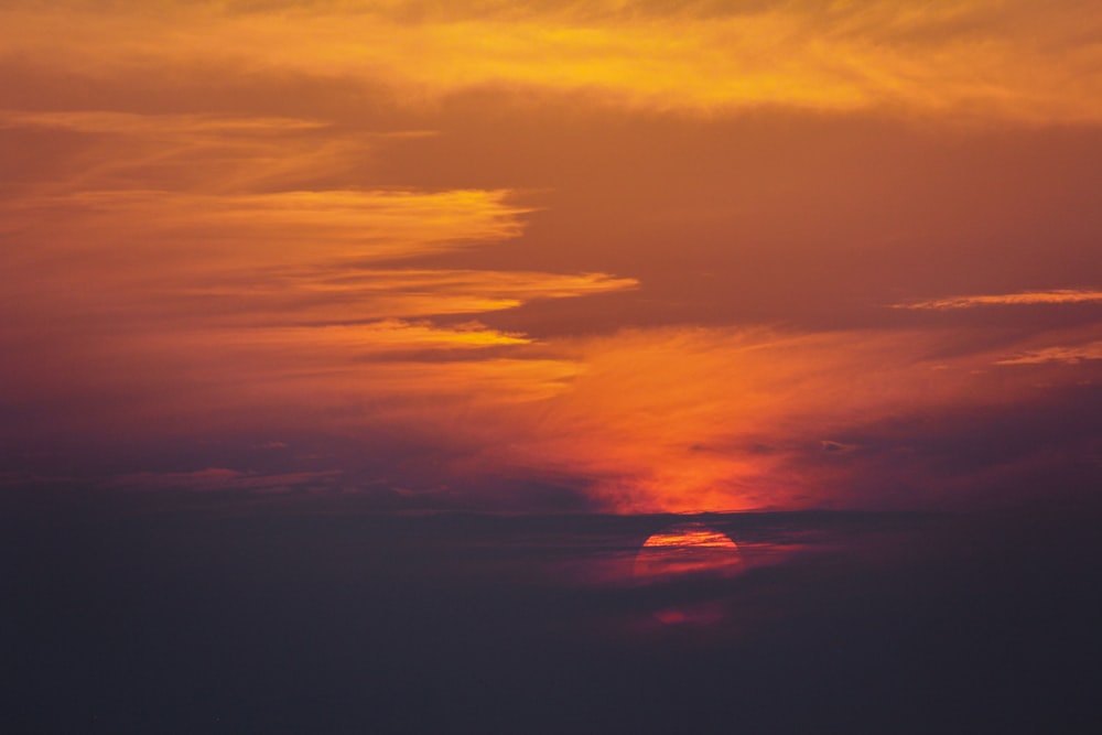 a plane flying in the sky at sunset