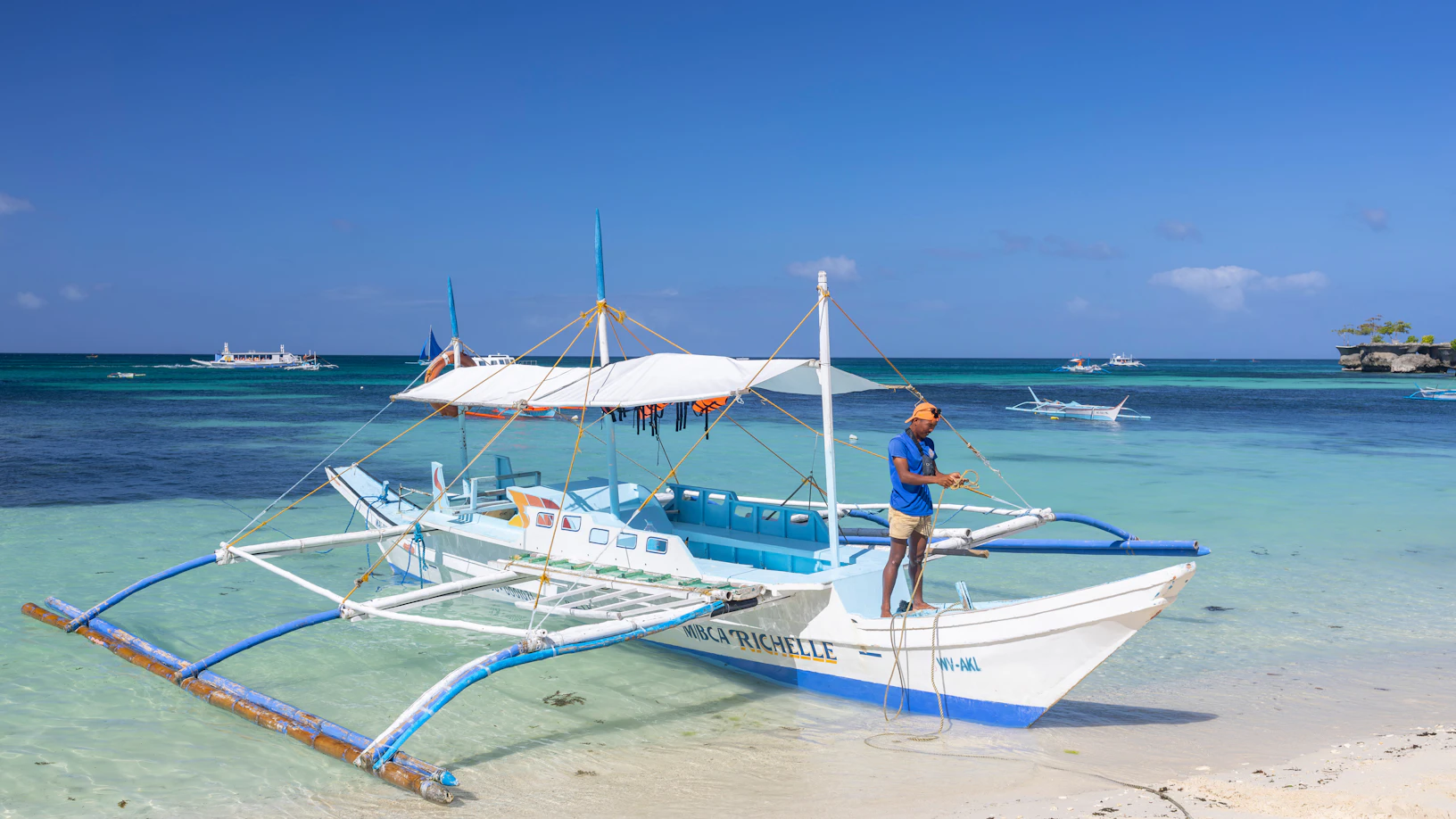 Traditional outrigger boats resting on turquoise water at sunset