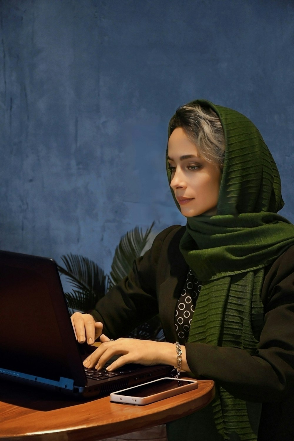 a woman sitting at a table using a laptop computer