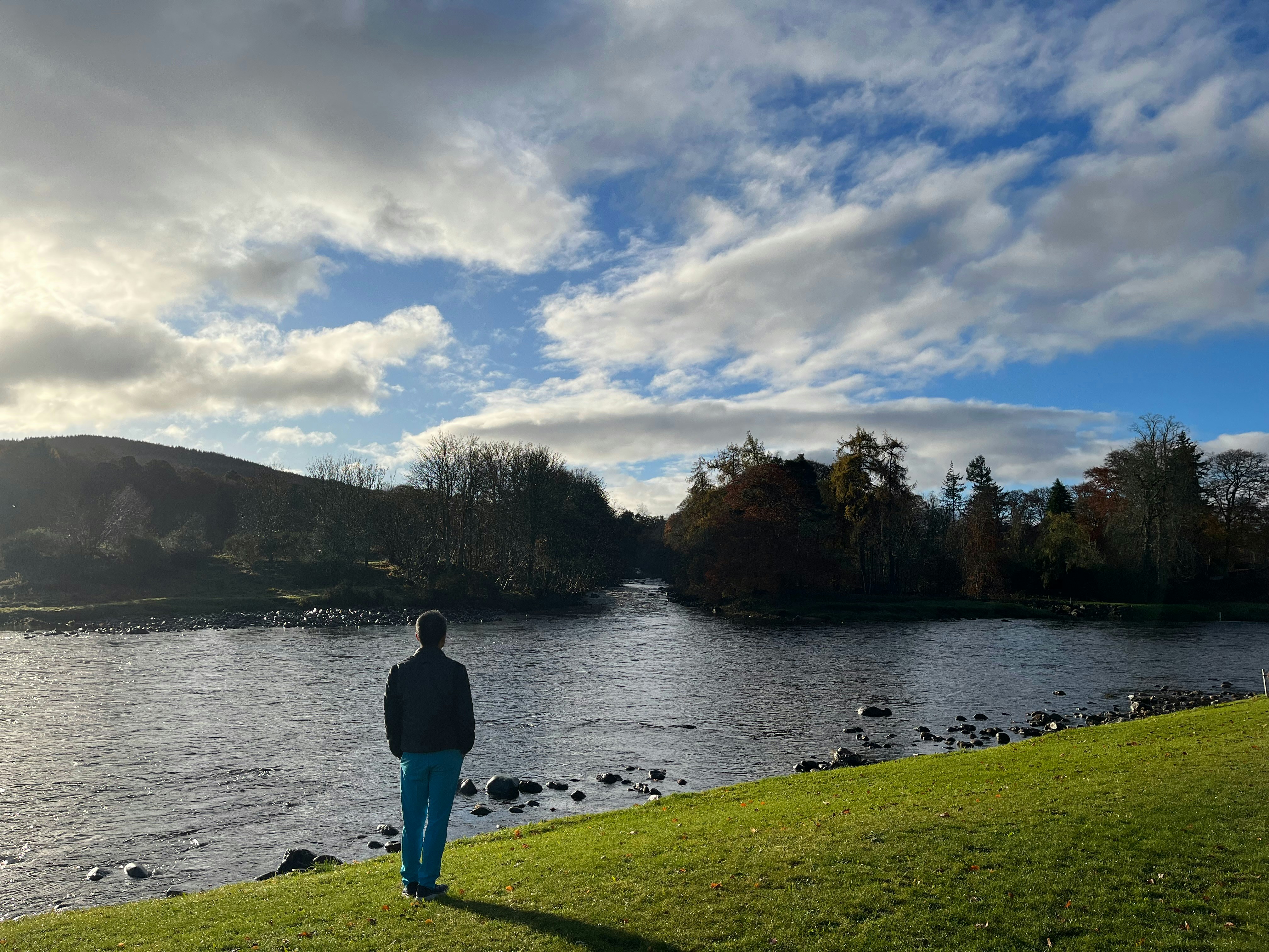 a person standing on a grassy hill next to a body of water