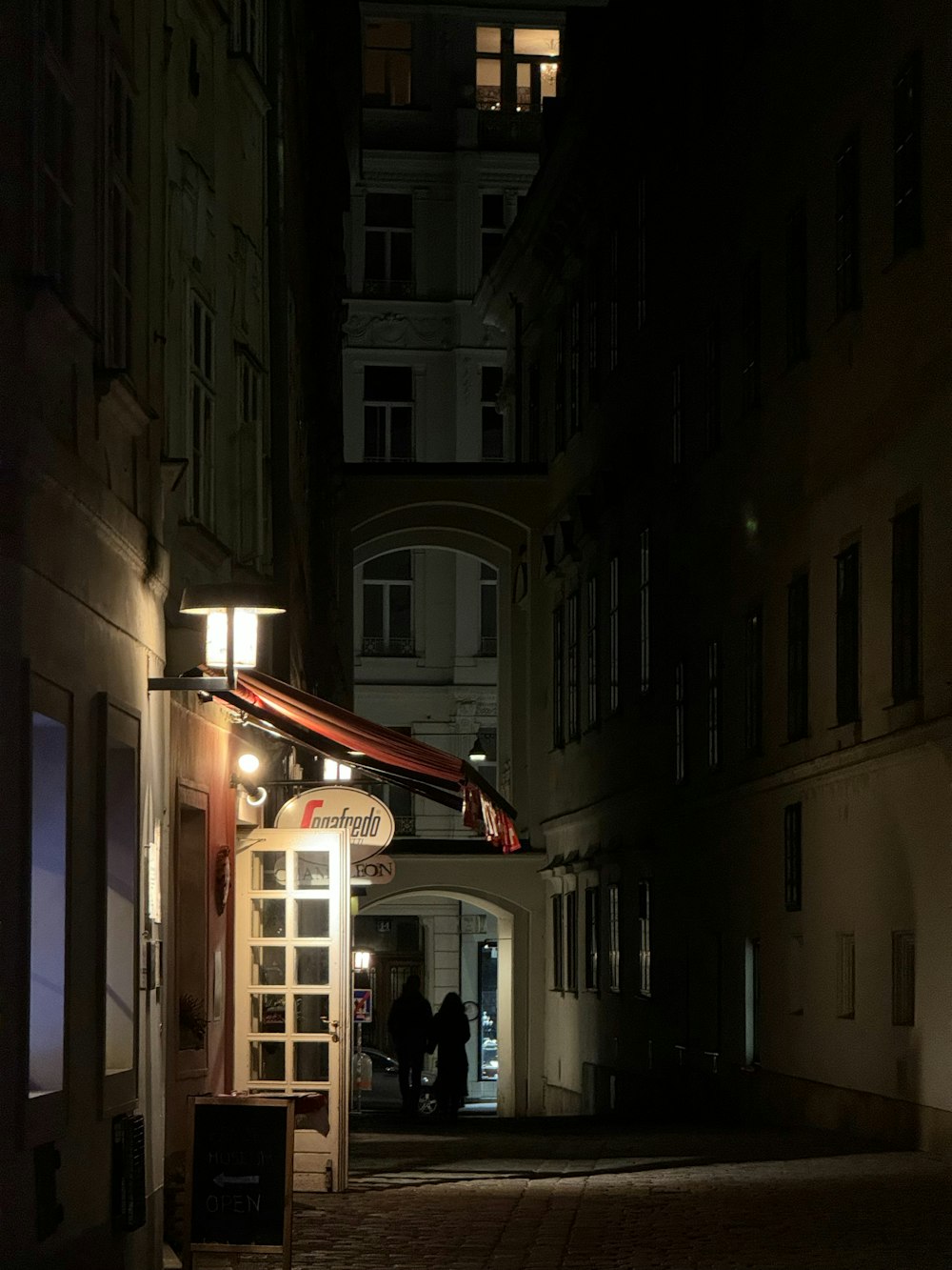 a couple of people standing outside of a building at night