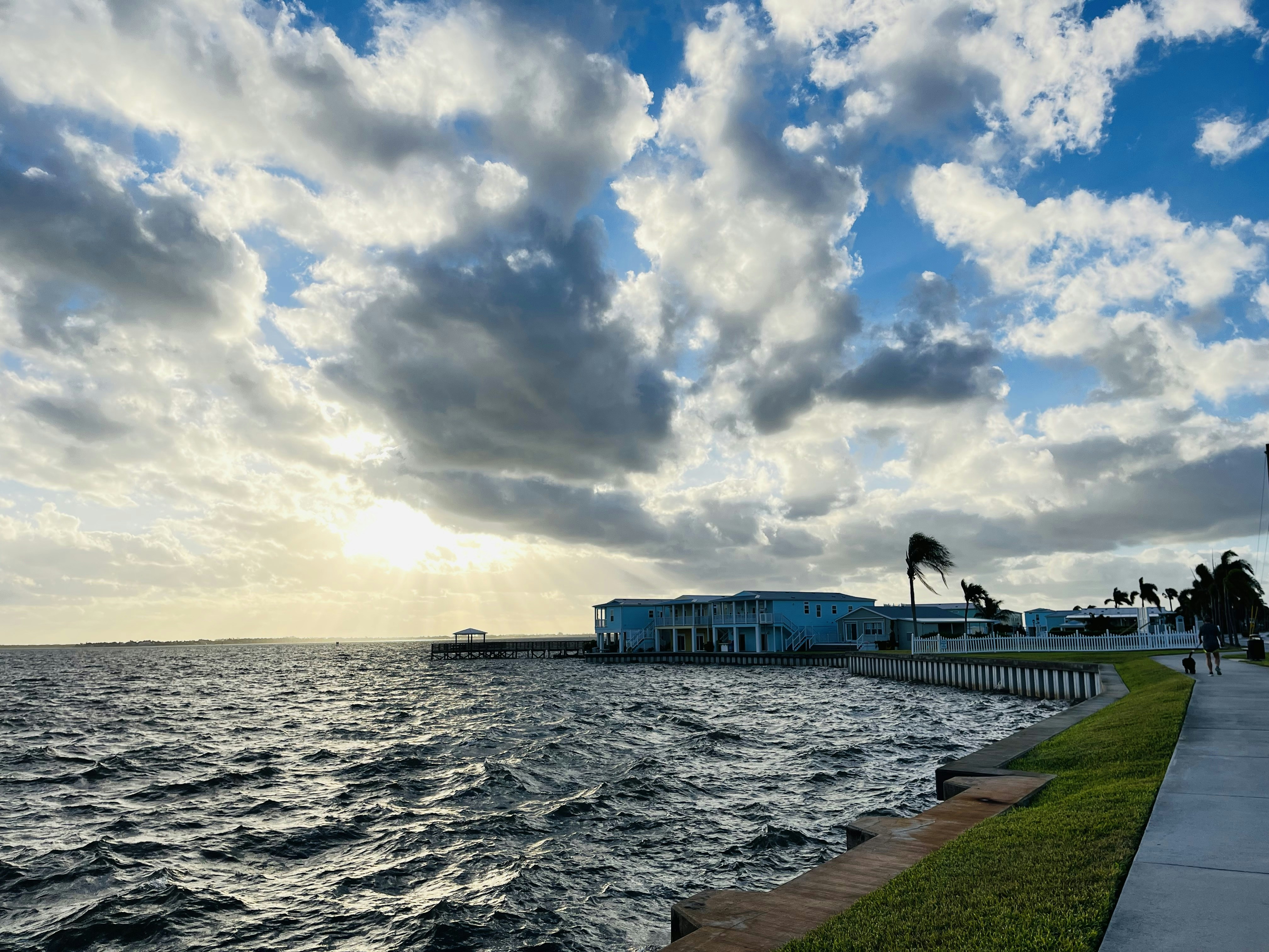 a body of water next to a beach with a sky filled with clouds