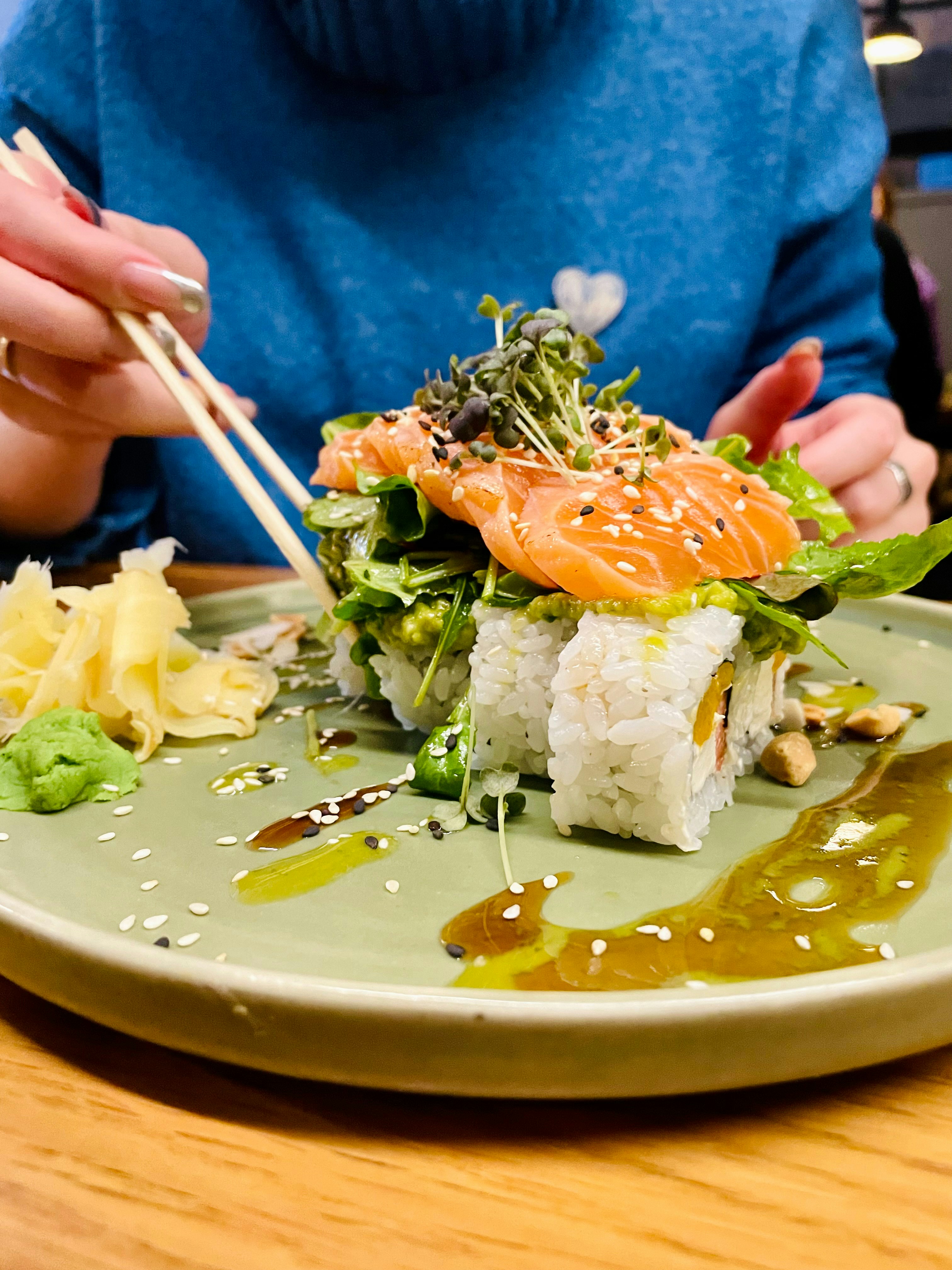 una mujer comiendo sushi con palillos en un plato