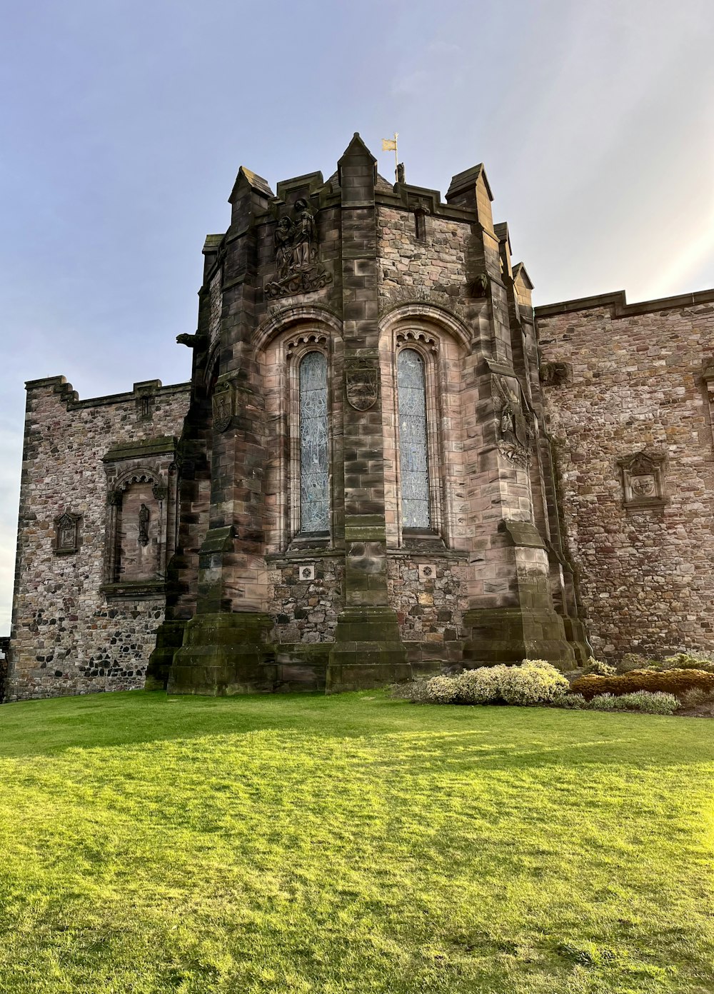 an old castle with a green lawn and a blue sky