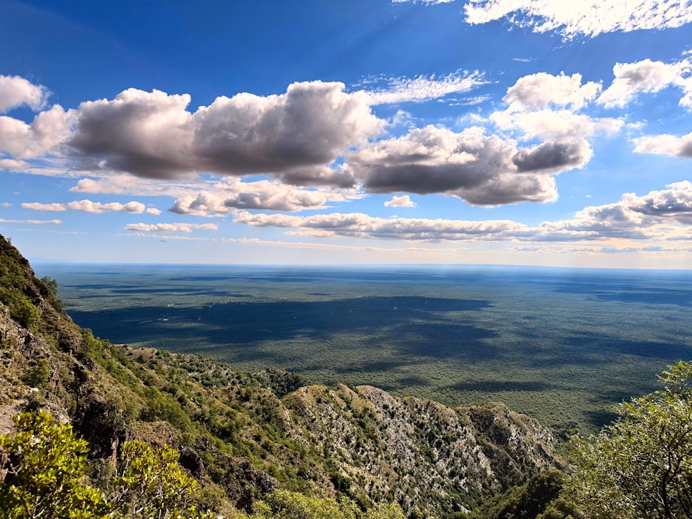 a scenic view of a valley and mountains under a cloudy blue sky