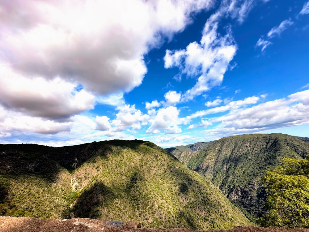 a scenic view of a mountain range under a cloudy blue sky