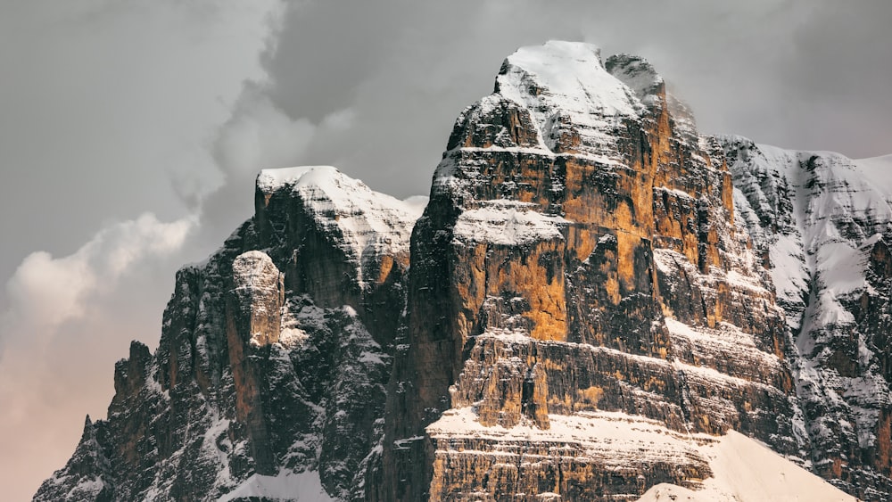 a mountain covered in snow under a cloudy sky