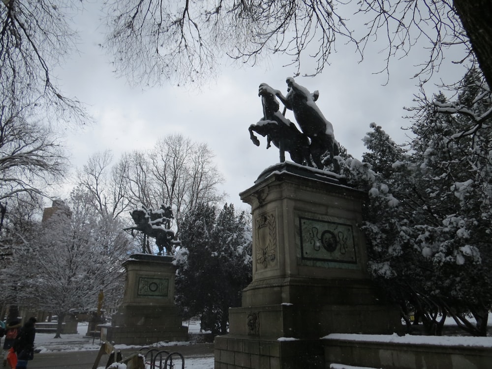 a statue of a man falling off a horse in a snowy park