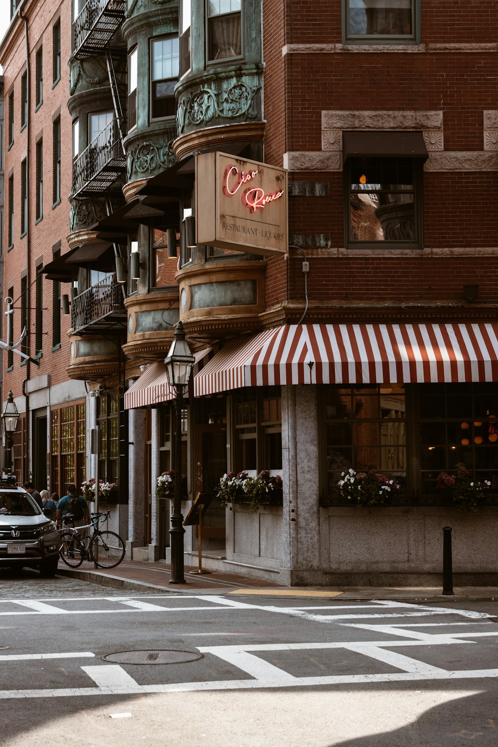 a street corner with a building and a car parked on the side of the road