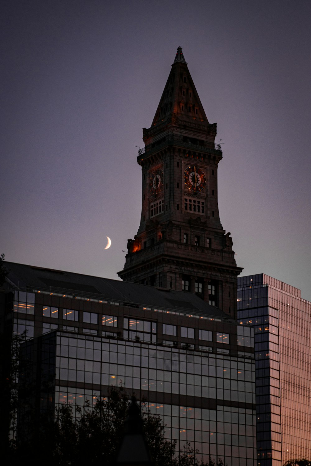 a tall clock tower with a half moon in the background