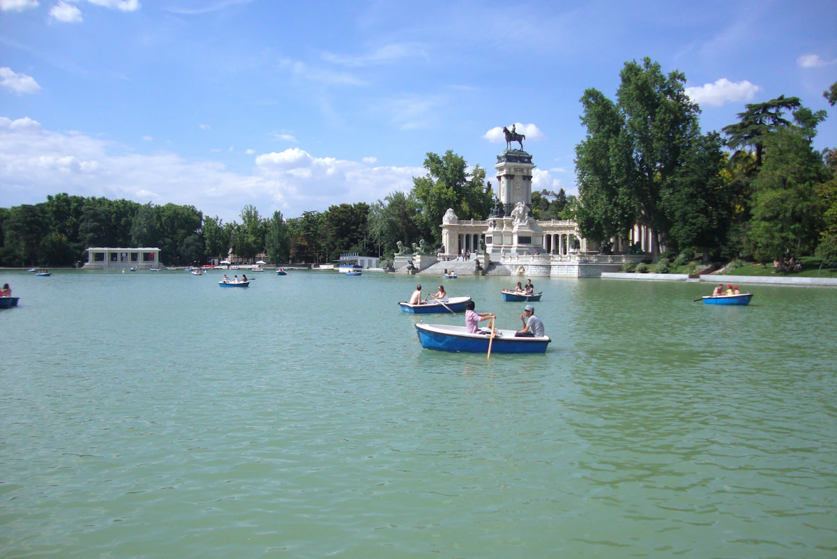 People rowing small boats on the lake in El Retiro Park