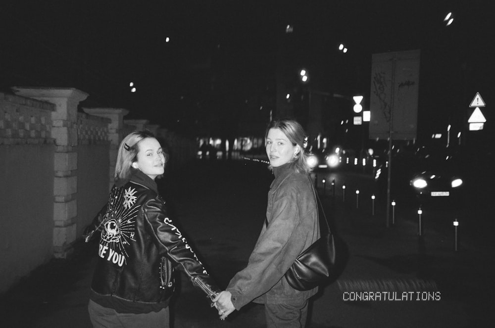 a couple of women walking down a street holding hands