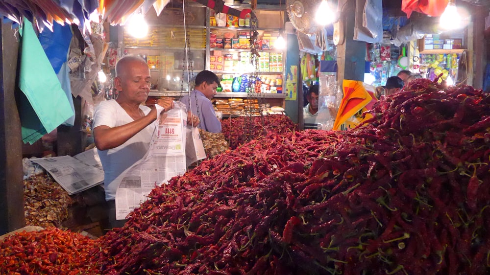 a man standing in front of a pile of dried red peppers