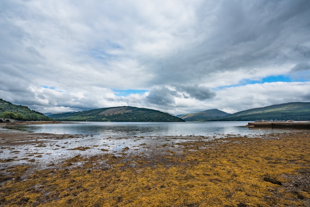 a body of water surrounded by mountains under a cloudy sky