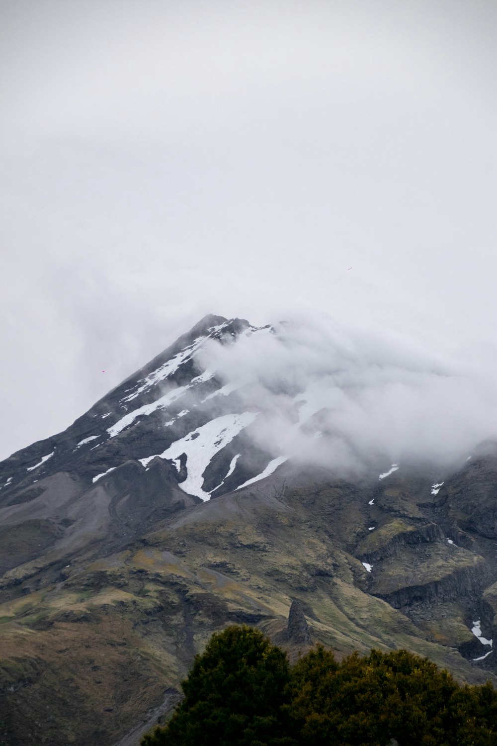 a mountain covered in snow and clouds on a cloudy day