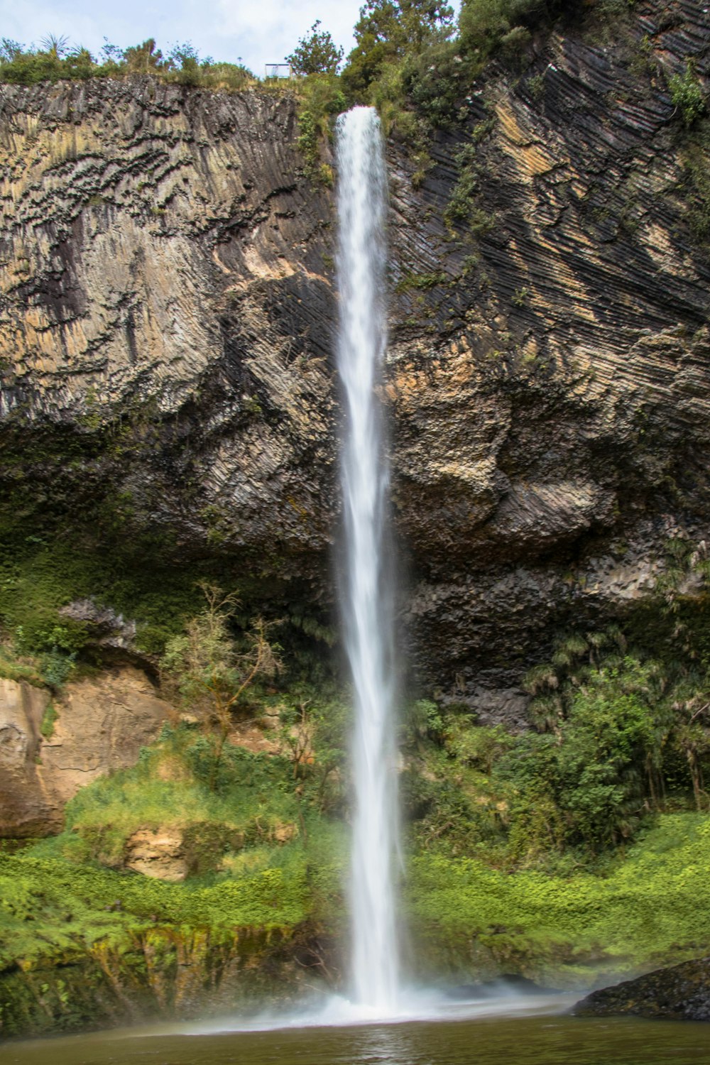 a very tall waterfall in the middle of a body of water