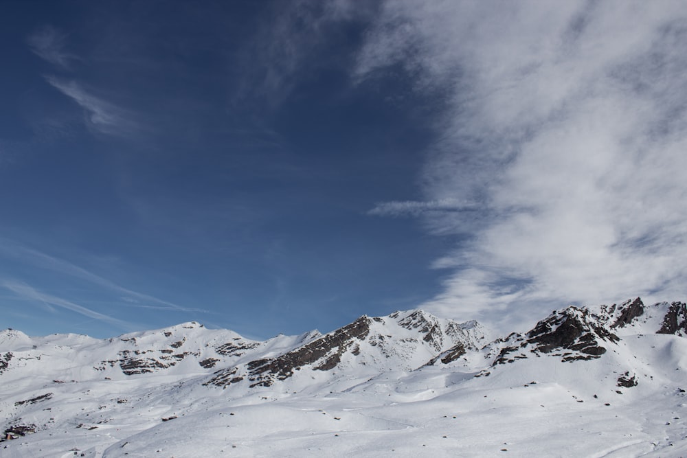 a mountain covered in snow under a cloudy blue sky