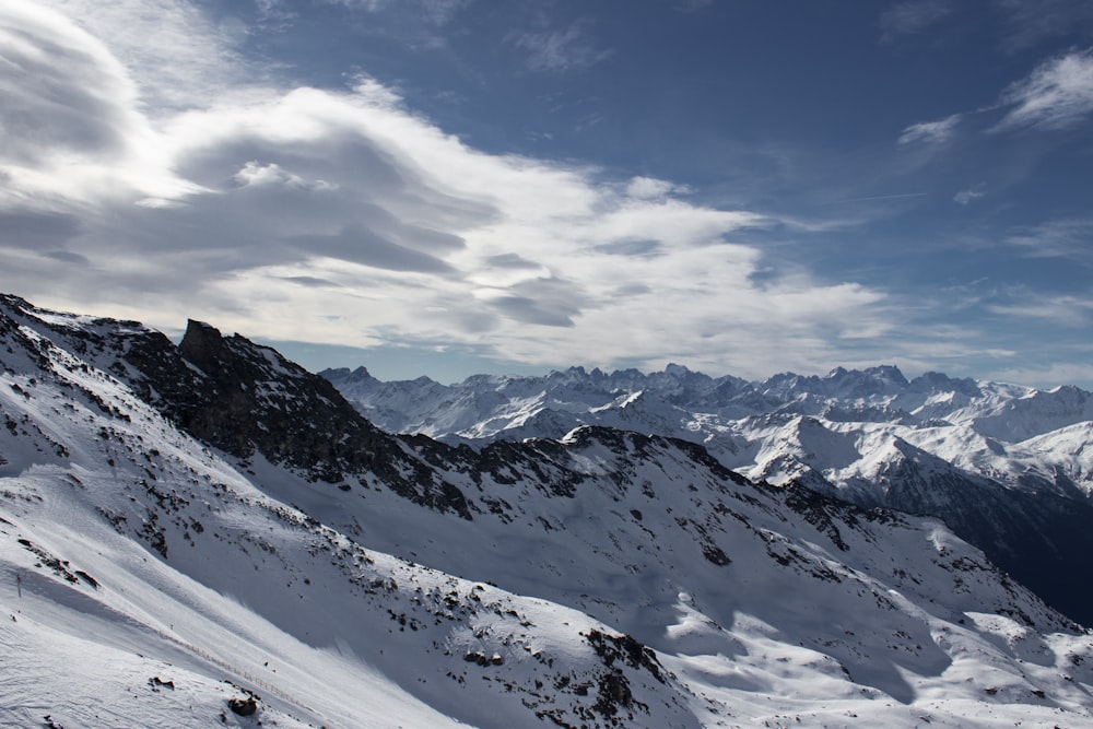 a view of a snowy mountain range with clouds in the sky
