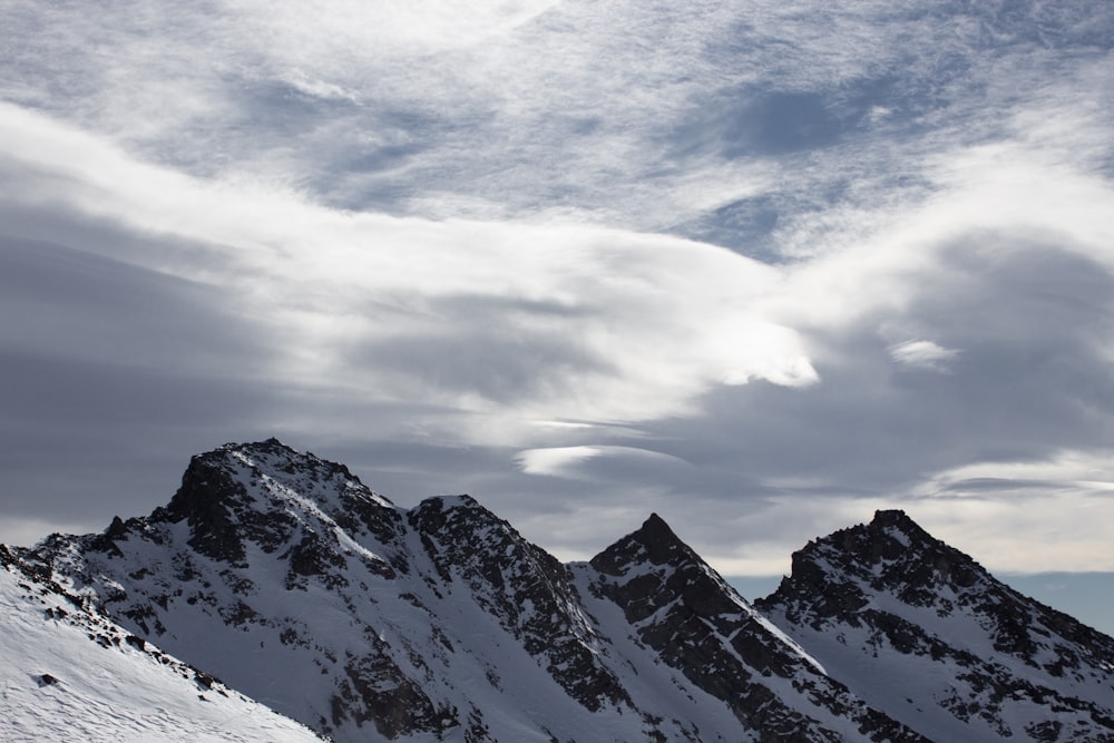 a group of snow covered mountains under a cloudy sky