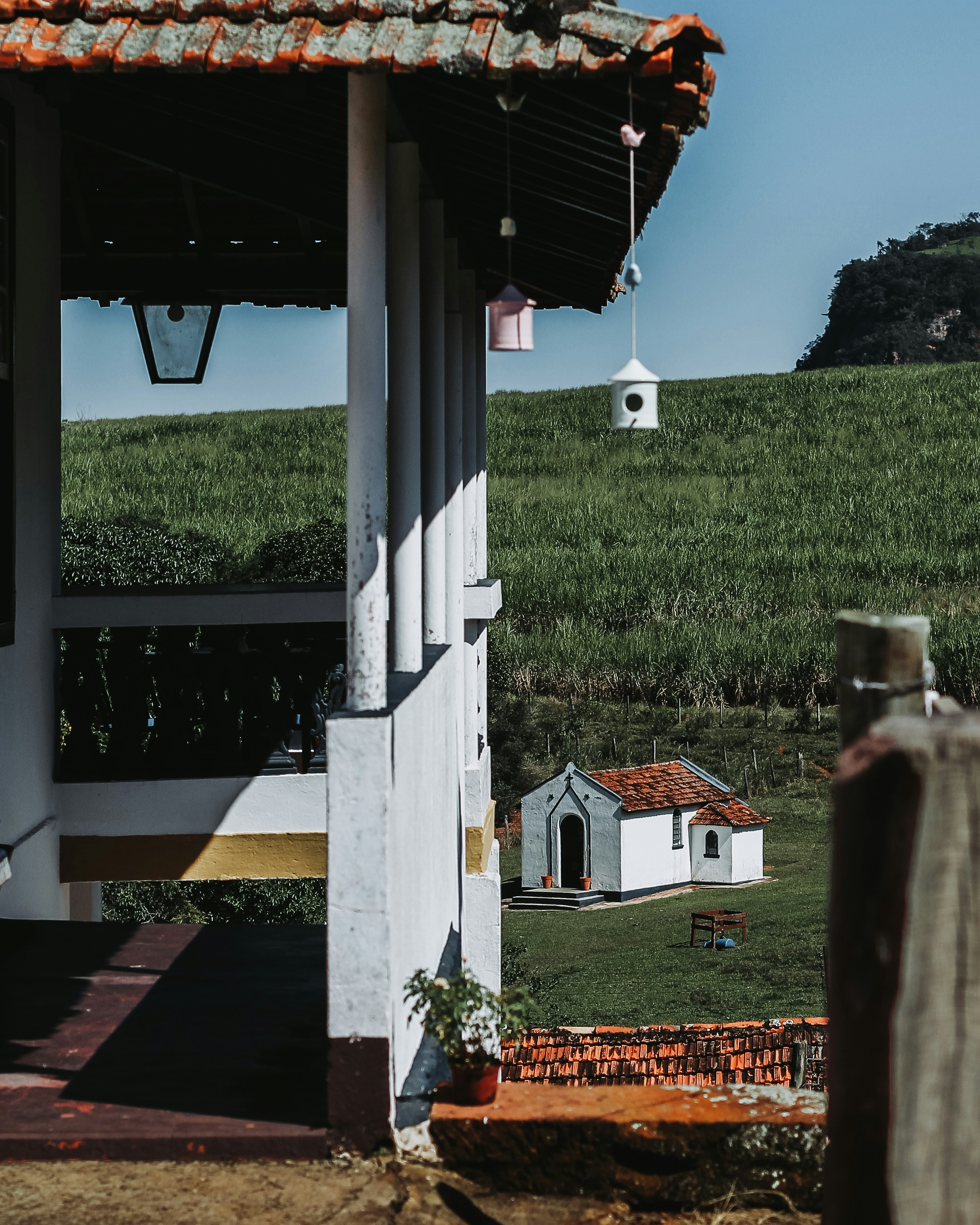 a small white house sitting on top of a lush green hillside