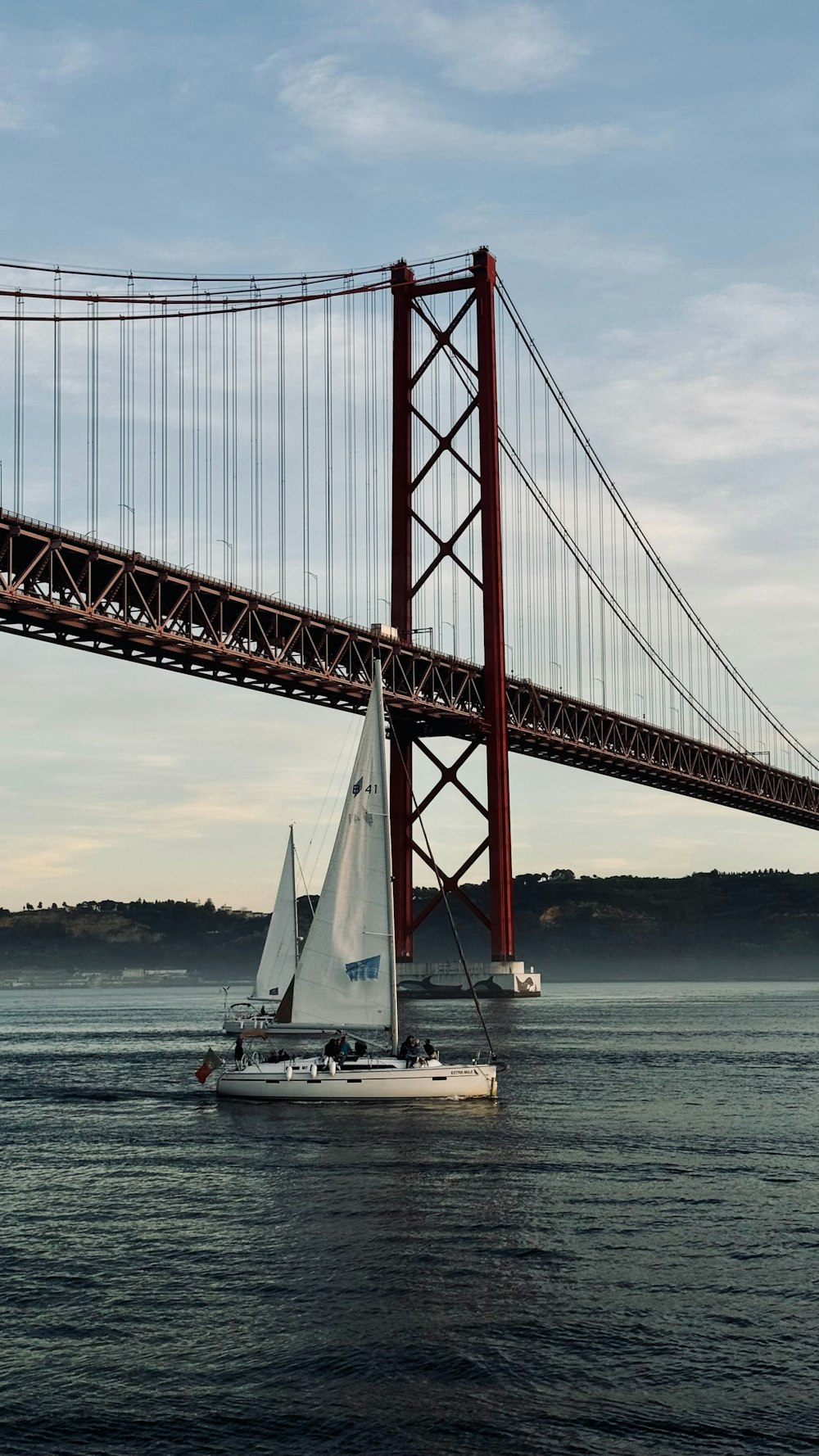 a sailboat in the water under a bridge