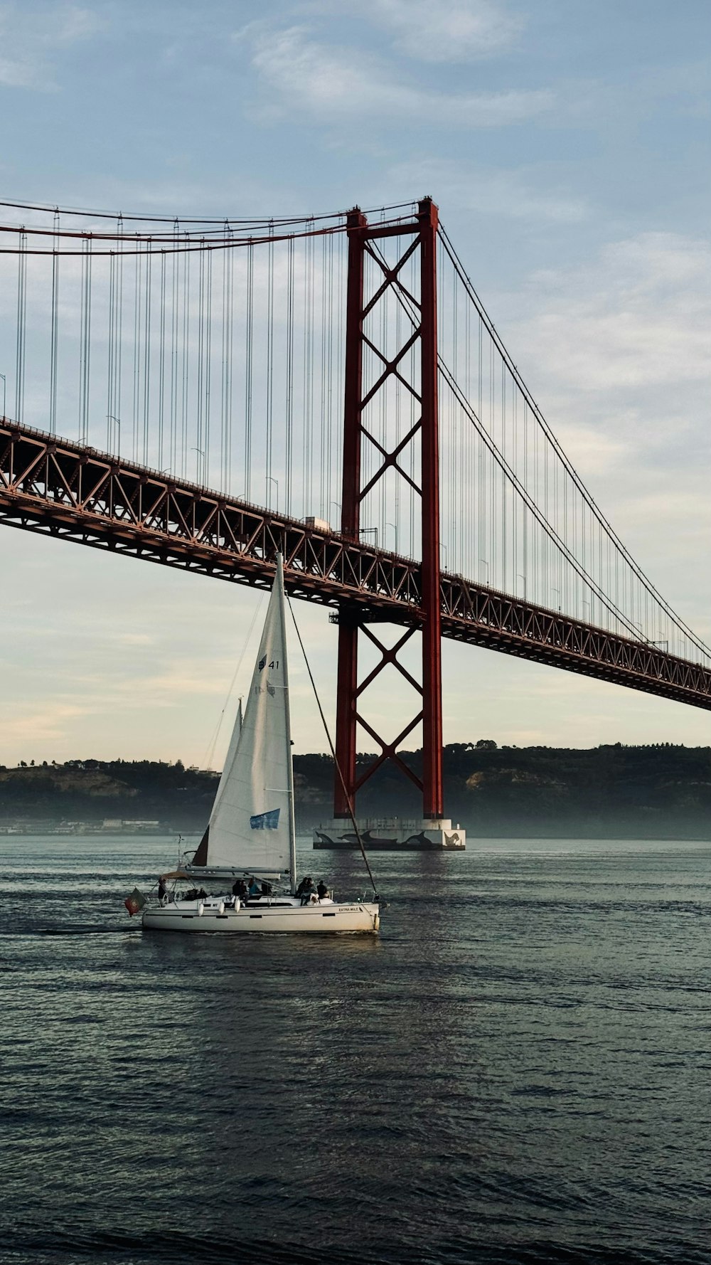 a sailboat in the water under a bridge