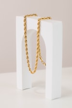 a gold rope necklace sitting on top of a white block