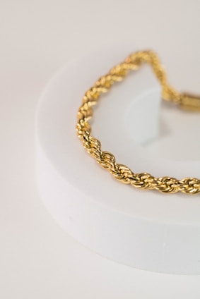 a close up of a gold bracelet on a white surface