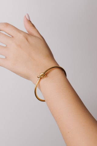 a woman's hand with a gold bracelet on it