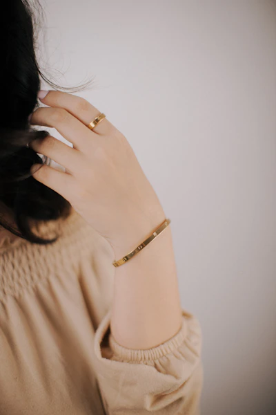 a woman wearing a gold bracelet and a gold ring