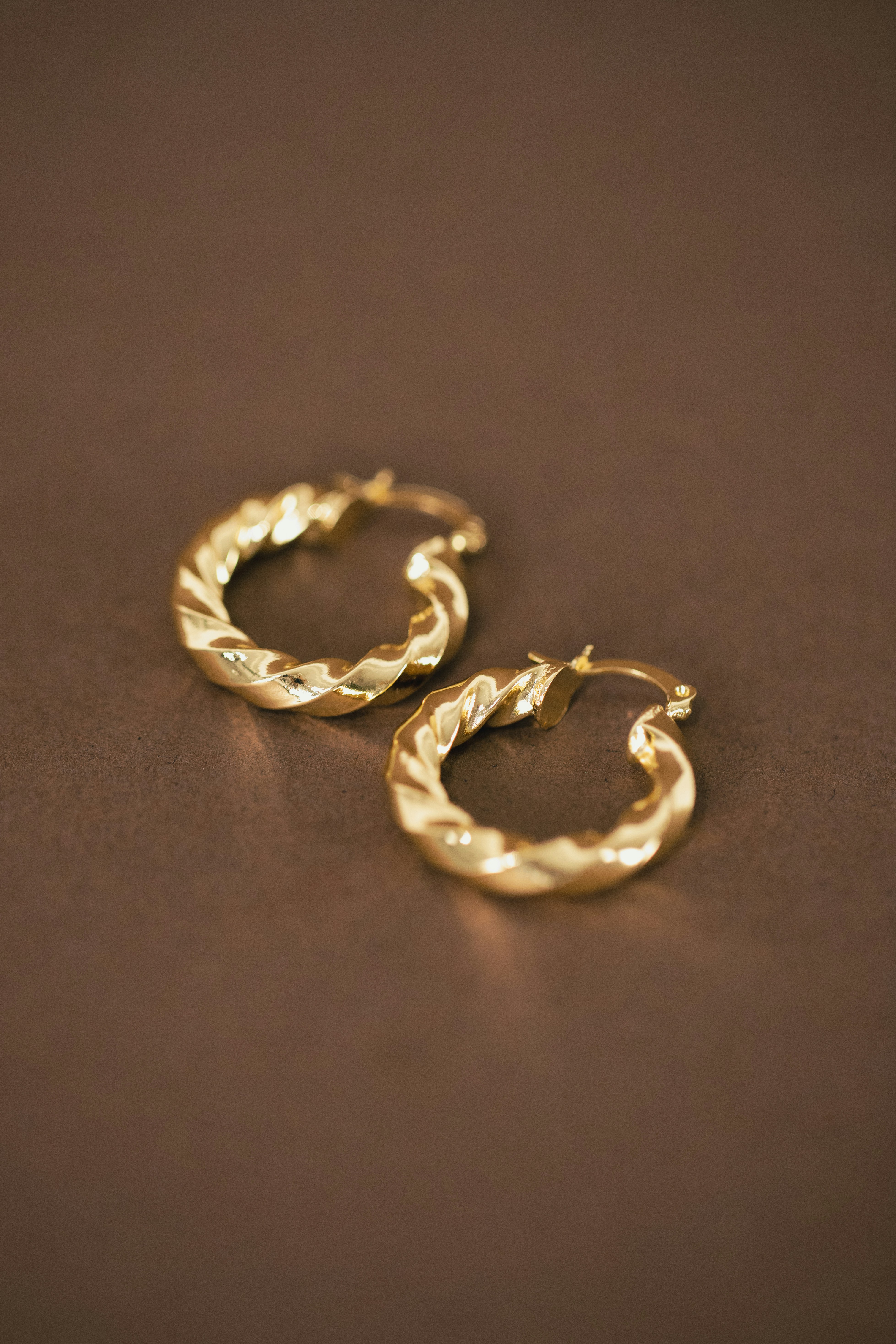 Pair of polished 24 K gold earrings stamped “999.9” resting on a dark surface.