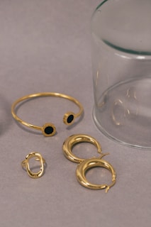 a pair of gold rings and a glass of water