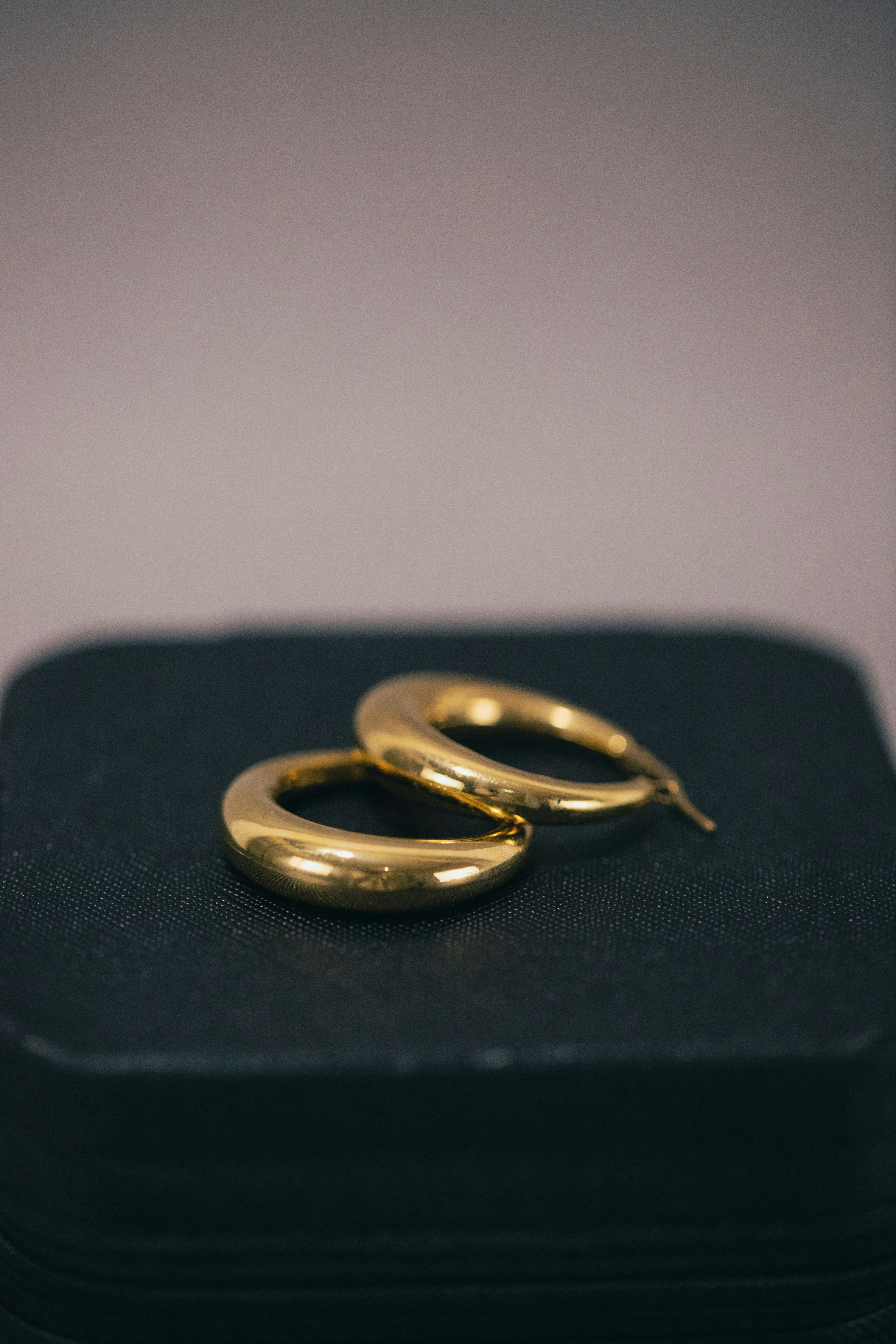 a pair of gold hoop earrings sitting on top of a black case
