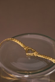 a gold necklace in a glass bowl on a table