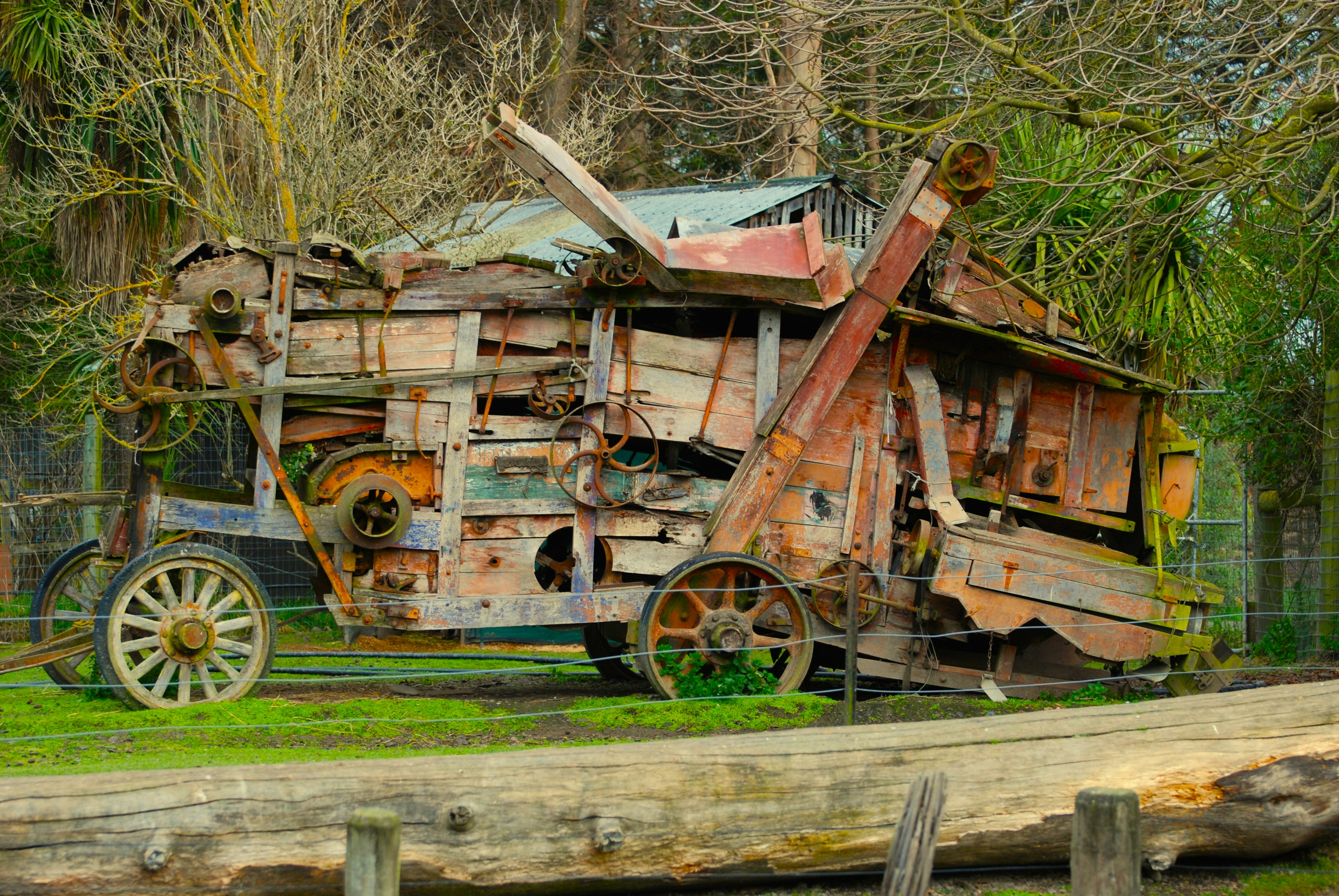 a rusted out truck sitting on top of a lush green field
